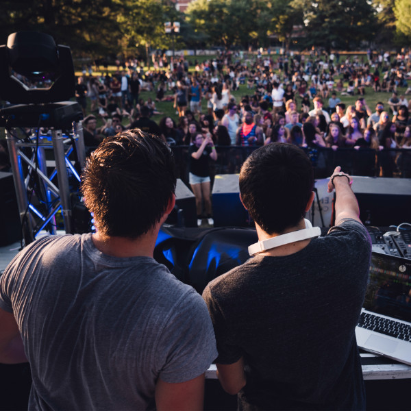 Dos djs de pie frente a una multitud de gente